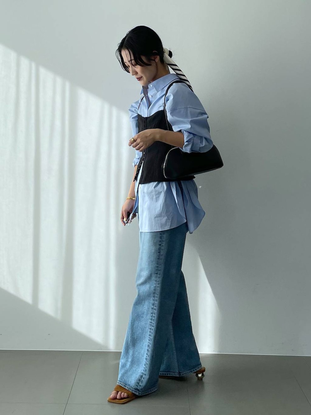 ブラック系のハンドバッグ、ブルー系のシャツ/ブラウス、ブルー系のデニムパンツを着用したレディースの冬コーディネートの4枚目の写真