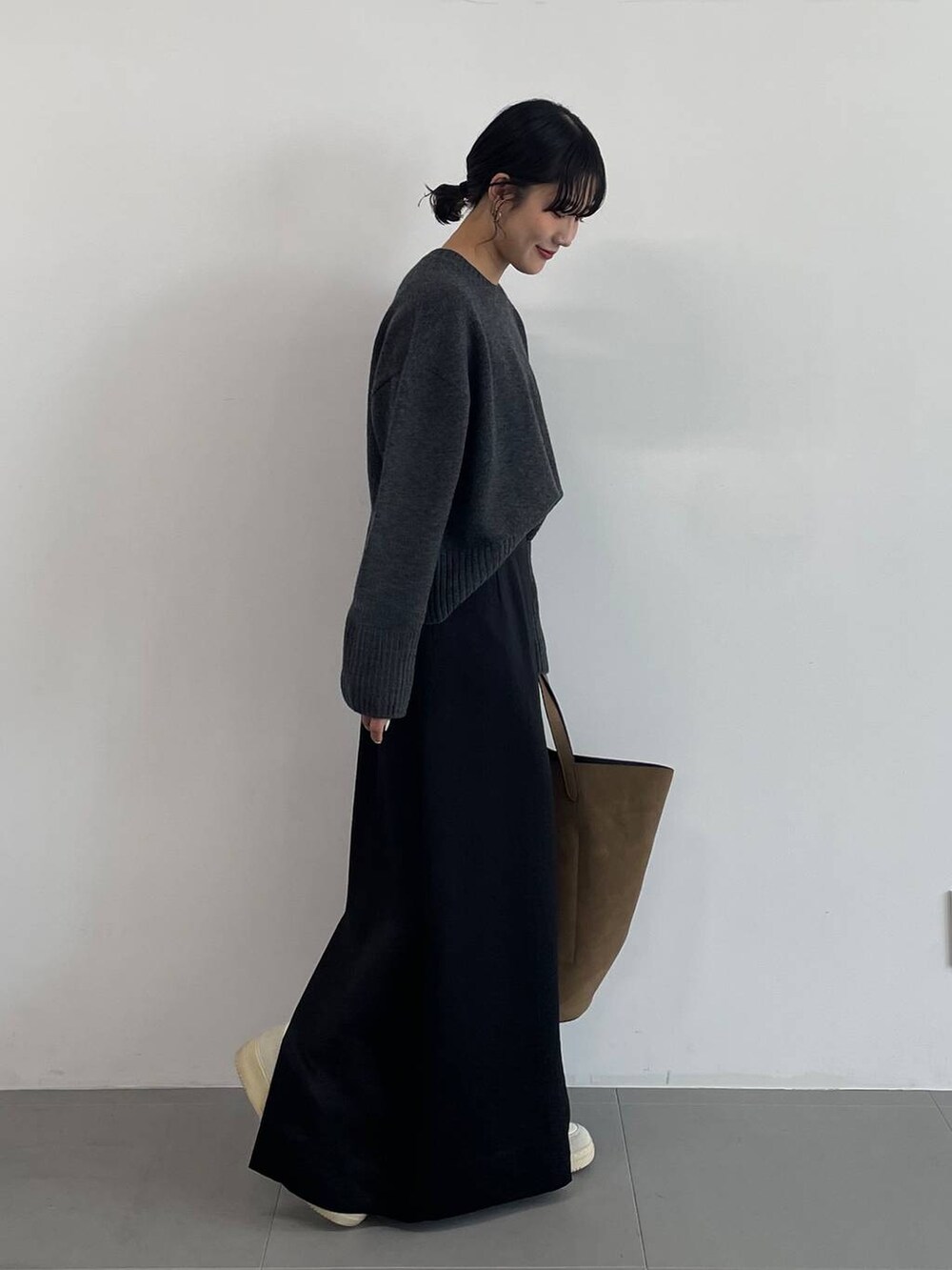 ブラウン系のトートバッグ、ブラック系のスカート、グレー系のニット/セーターを着用したレディースの冬コーディネートの3枚目の写真