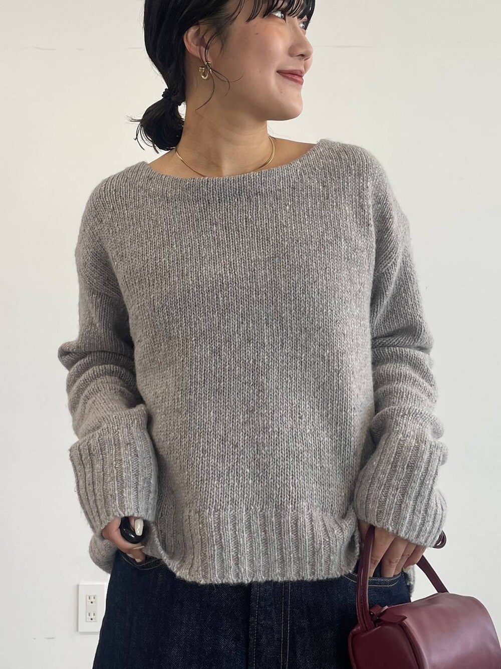 レッド系のショルダーバッグ、ブラック系のローファー、ブルー系のデニムパンツを着用したレディースの冬コーディネートの5枚目の写真