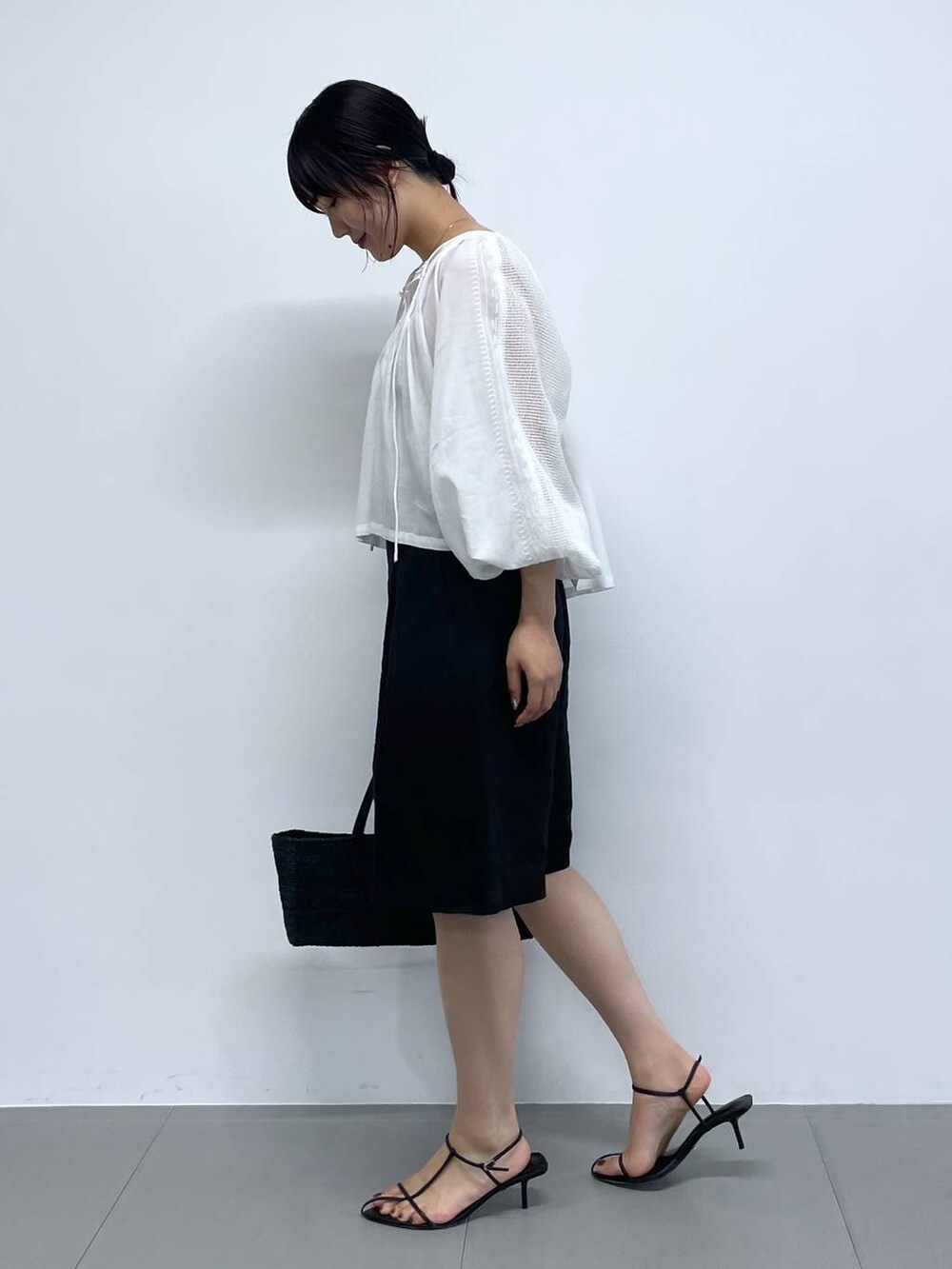 ブラック系のかごバッグ、ホワイト系のシャツ/ブラウス、ブラック系のサンダルを着用したレディースの夏コーディネートの2枚目の写真
