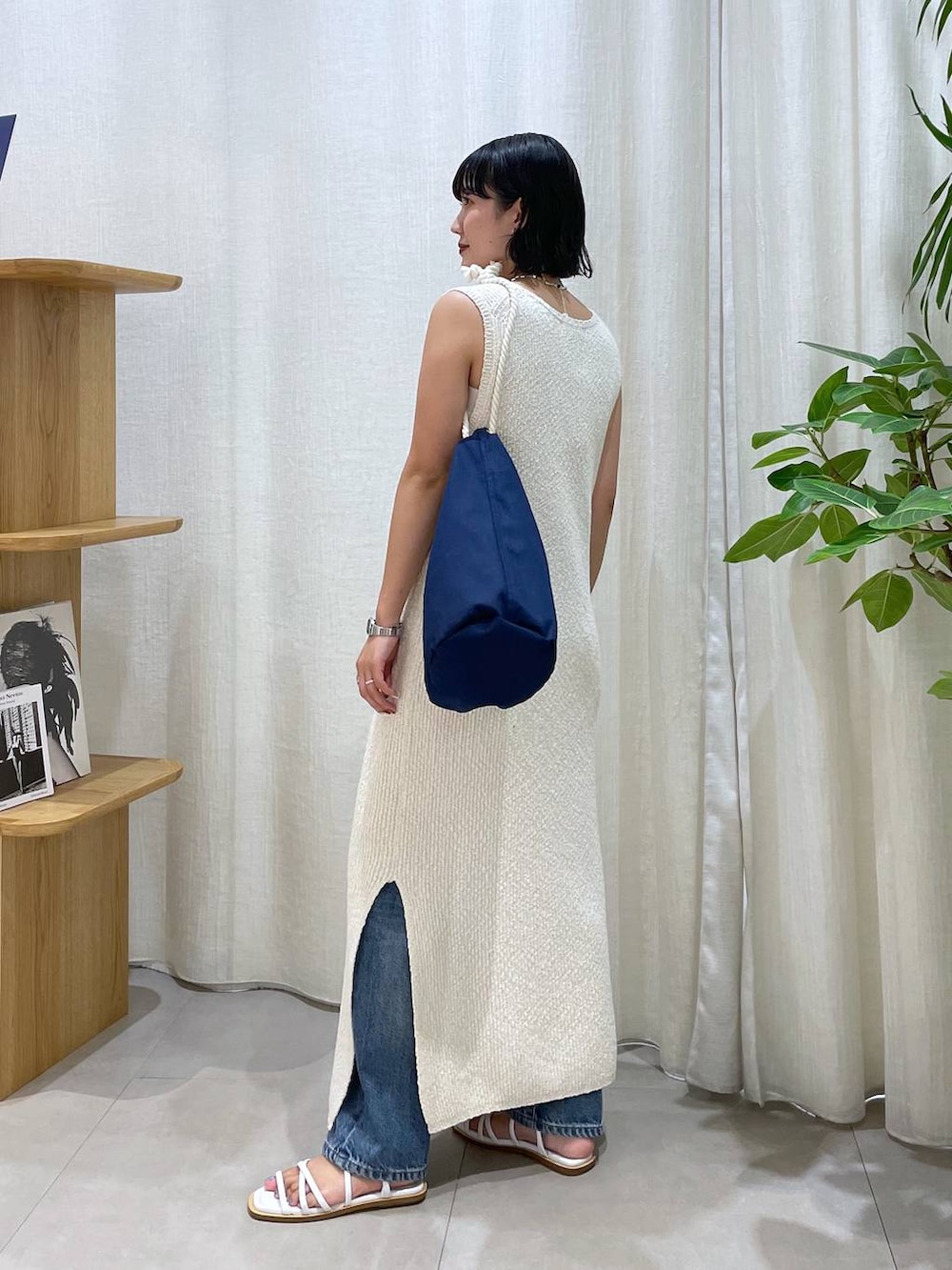 ブルー系のハンドバッグ、ホワイト系のサンダル、ブルー系のデニムパンツを着用したレディースの夏コーディネートの3枚目の写真