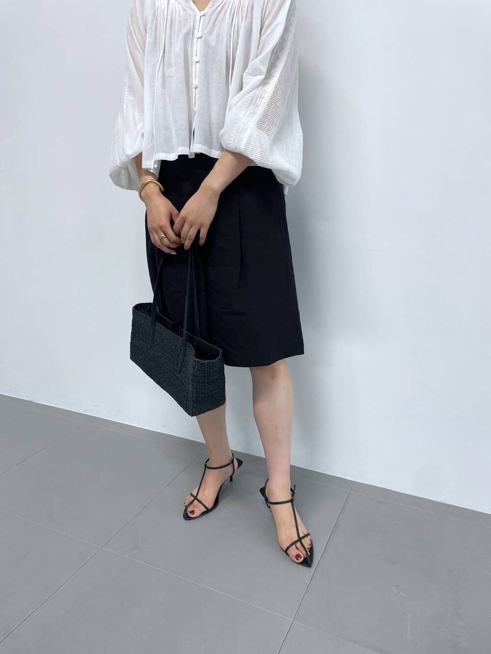 ブラック系のかごバッグ、ホワイト系のシャツ/ブラウス、ブラック系のサンダルを着用したレディースの夏コーディネートの5枚目の写真