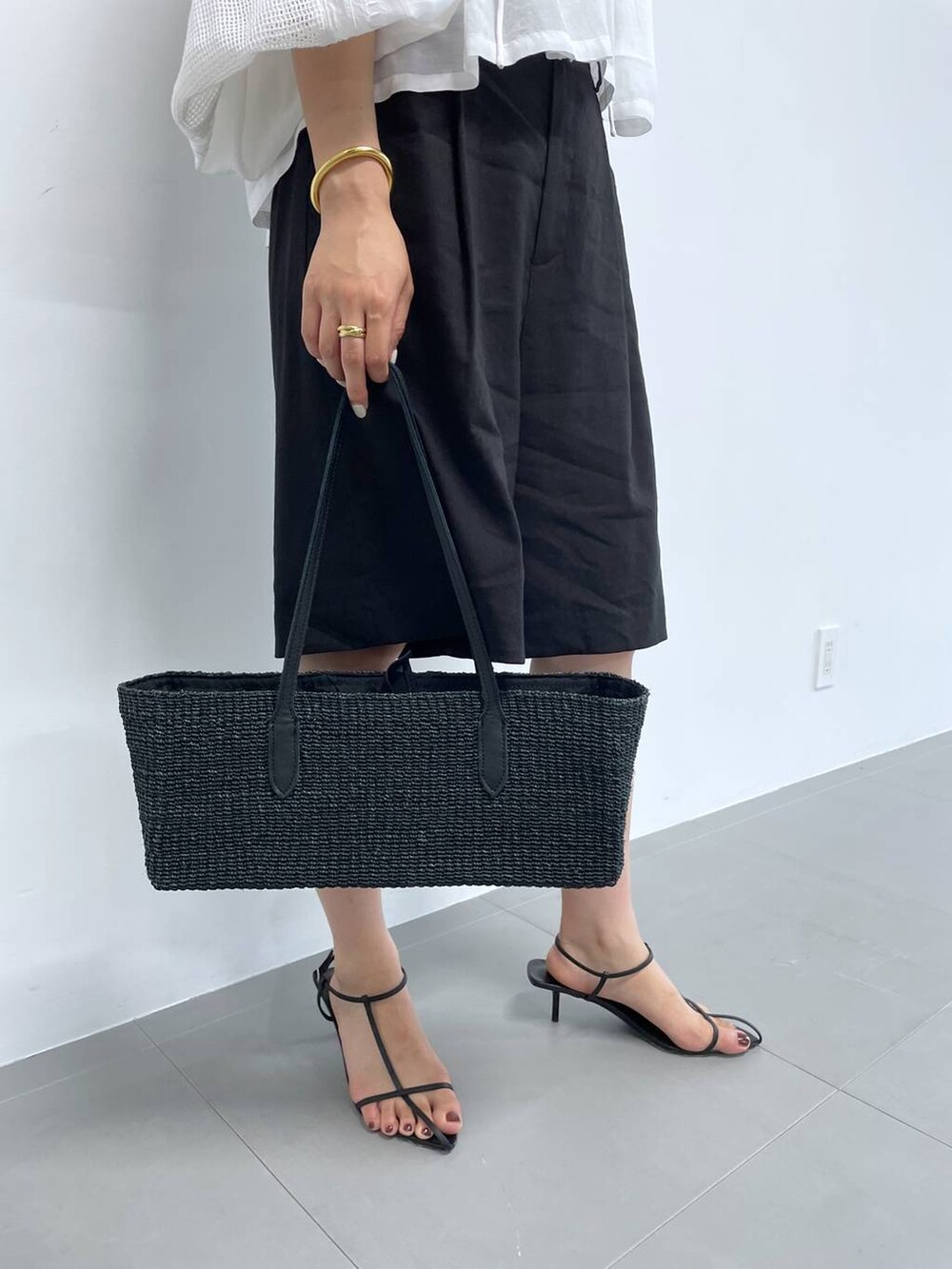 ブラック系のかごバッグ、ホワイト系のシャツ/ブラウス、ブラック系のサンダルを着用したレディースの夏コーディネートの4枚目の写真