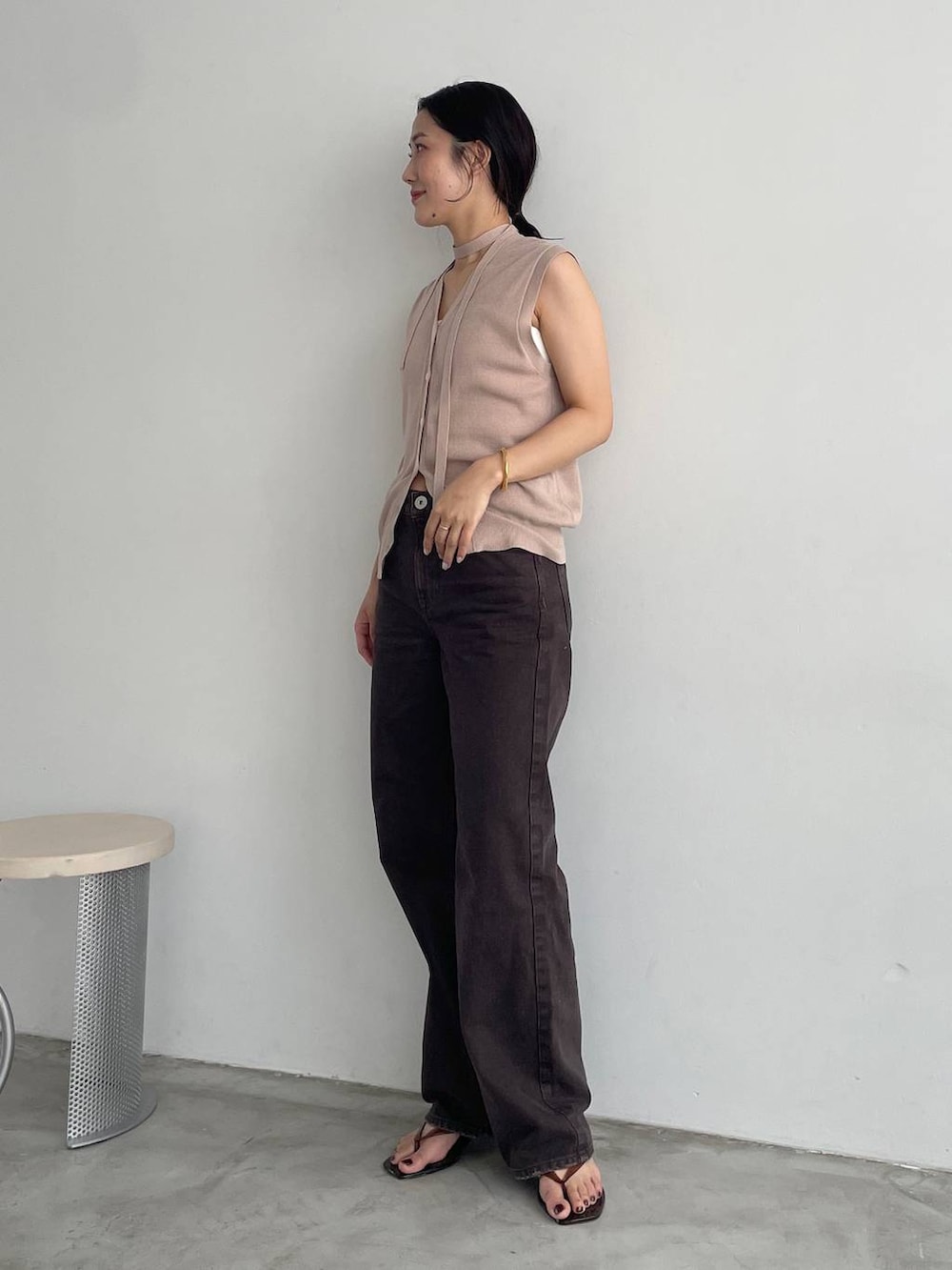 ホワイト系のキャミソール、ブラウン系のデニムパンツ、ベージュ系のニット/セーターを着用したレディースの夏コーディネートの2枚目の写真
