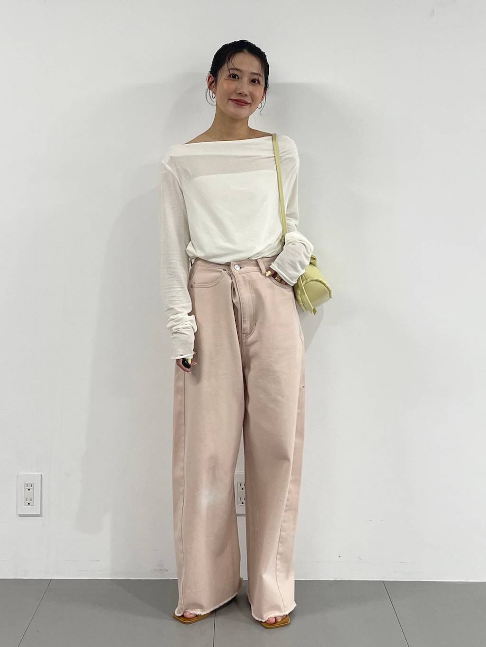 ピンク系のデニムパンツ、イエロー系のハンドバッグ、ホワイト系のTシャツ/カットソーを着用したレディースの冬コーディネートの2枚目の写真