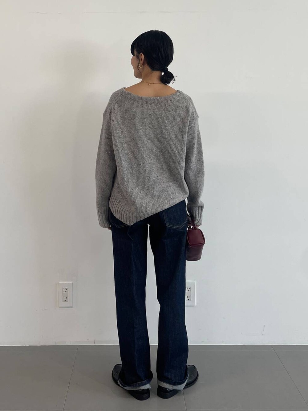 レッド系のショルダーバッグ、ブラック系のローファー、ブルー系のデニムパンツを着用したレディースの冬コーディネートの4枚目の写真