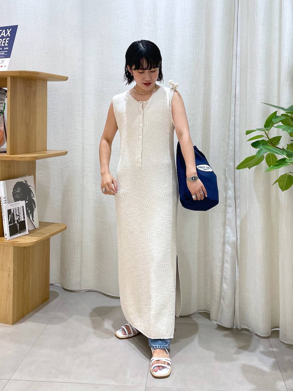 ブルー系のハンドバッグ、ホワイト系のサンダル、ブルー系のデニムパンツを着用したレディースの夏コーディネートの2枚目の写真