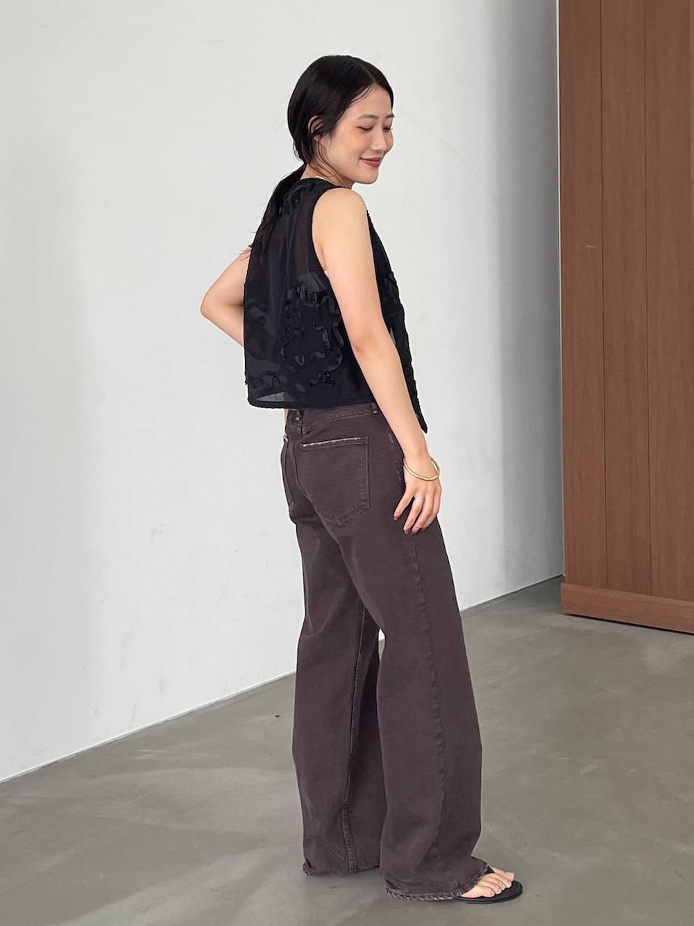 ブラック系のスリッポン、ブラウン系のタンクトップ、ブラウン系のデニムパンツを着用したレディースの夏コーディネートの3枚目の写真