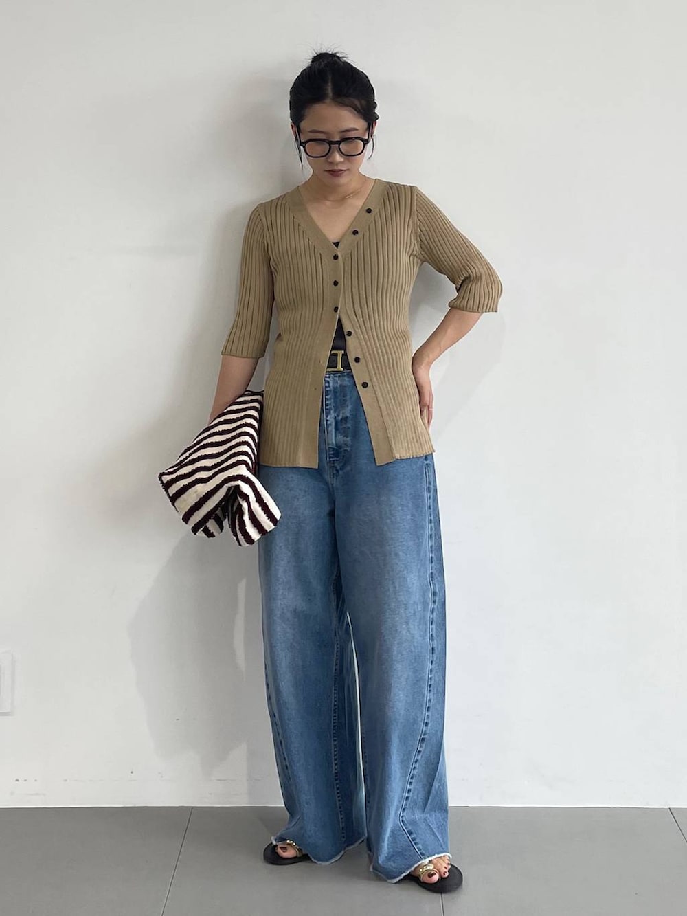 ブルー系のデニムパンツ、ブラック系のサンダル、ベージュ系のカーディガン/ボレロを着用したレディースの夏コーディネートの2枚目の写真