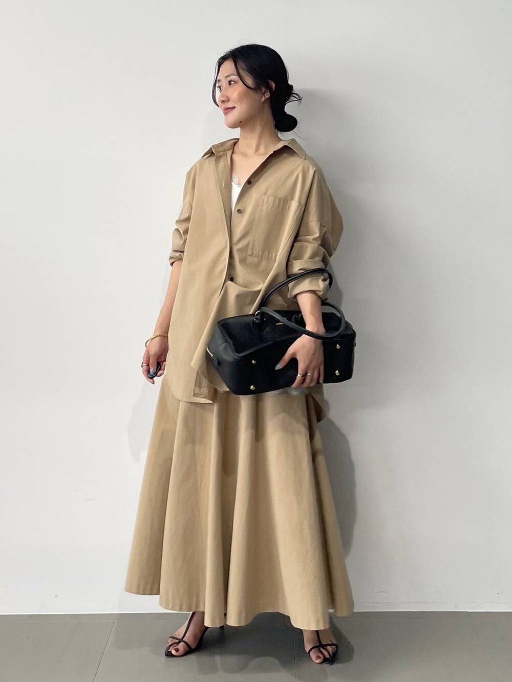 ブラック系のサンダル、ベージュ系のスカート、ベージュ系のシャツ/ブラウスを着用したレディースの春コーディネートの2枚目の写真