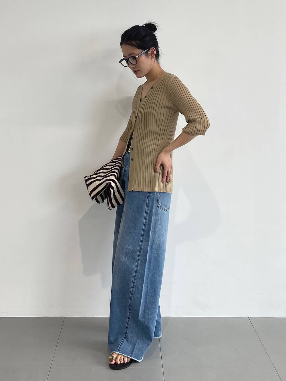 ブルー系のデニムパンツ、ブラック系のサンダル、ベージュ系のカーディガン/ボレロを着用したレディースの夏コーディネートの4枚目の写真