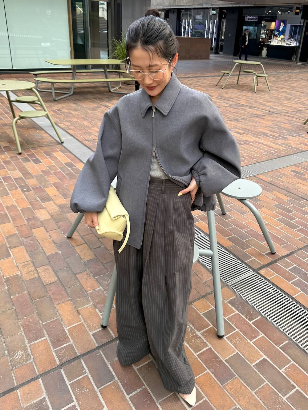 ベージュ系のパンプス、イエロー系のハンドバッグ、グレー系のTシャツ/カットソーを着用したレディースの春コーディネートの3枚目の写真