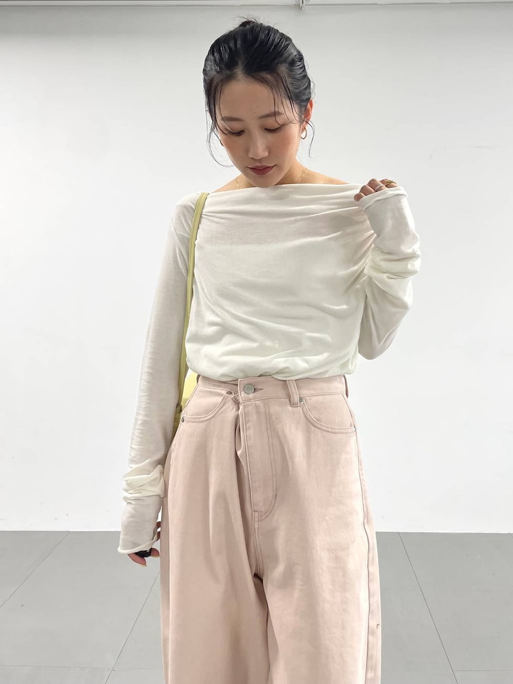 ピンク系のデニムパンツ、イエロー系のハンドバッグ、ホワイト系のTシャツ/カットソーを着用したレディースの冬コーディネートの7枚目の写真