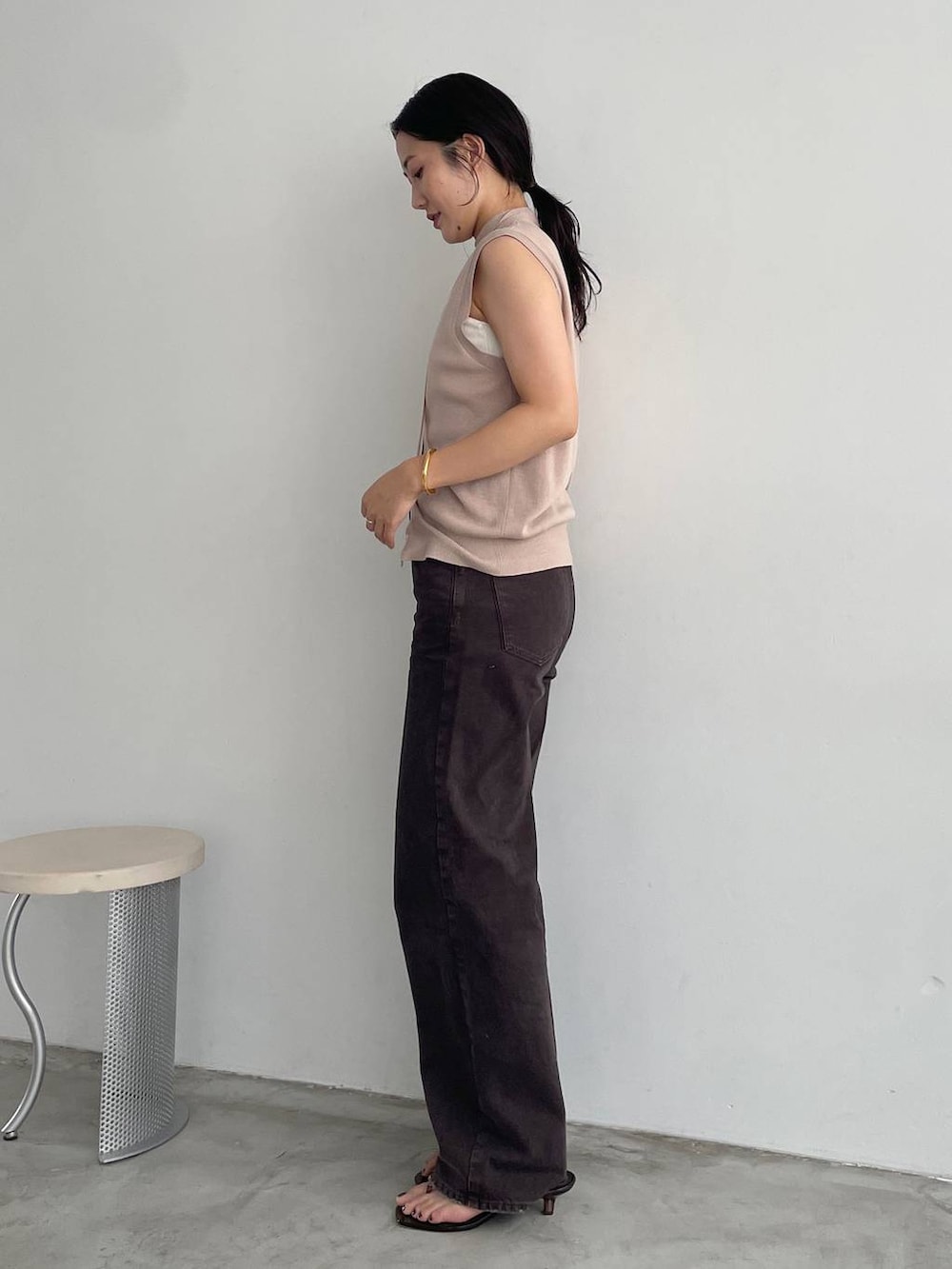 ホワイト系のキャミソール、ブラウン系のデニムパンツ、ベージュ系のニット/セーターを着用したレディースの夏コーディネートの3枚目の写真