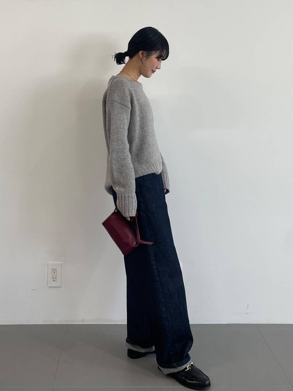 レッド系のショルダーバッグ、ブラック系のローファー、ブルー系のデニムパンツを着用したレディースの冬コーディネートの3枚目の写真