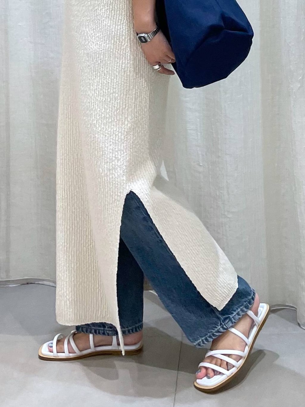 ブルー系のハンドバッグ、ホワイト系のサンダル、ブルー系のデニムパンツを着用したレディースの夏コーディネートの5枚目の写真