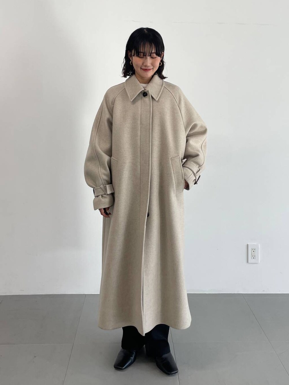 ブラック系のその他パンツ、ベージュ系のステンカラーコート、ベージュ系のニット/セーターを着用したレディースの冬コーディネートの4枚目の写真