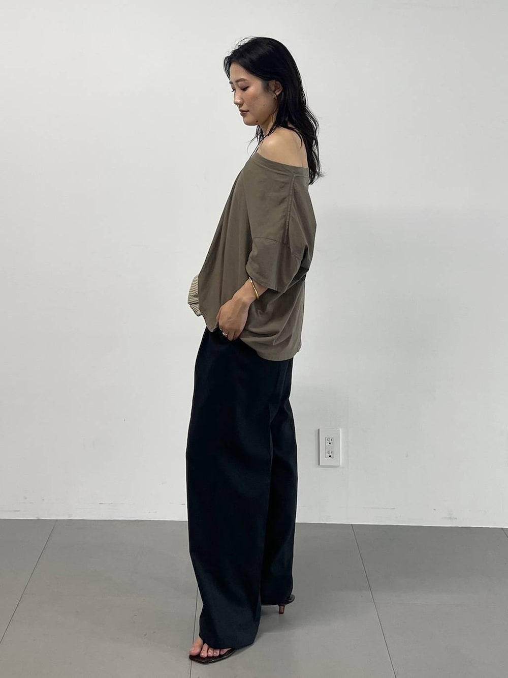 ブラック系のスラックス、グリーン系のTシャツ/カットソー、ブラック系のサンダルを着用したレディースの夏コーディネートの2枚目の写真