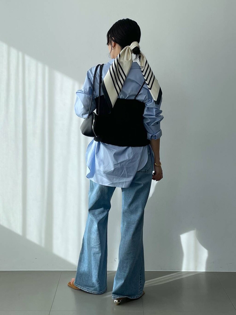 ブラック系のハンドバッグ、ブルー系のシャツ/ブラウス、ブルー系のデニムパンツを着用したレディースの冬コーディネートの5枚目の写真