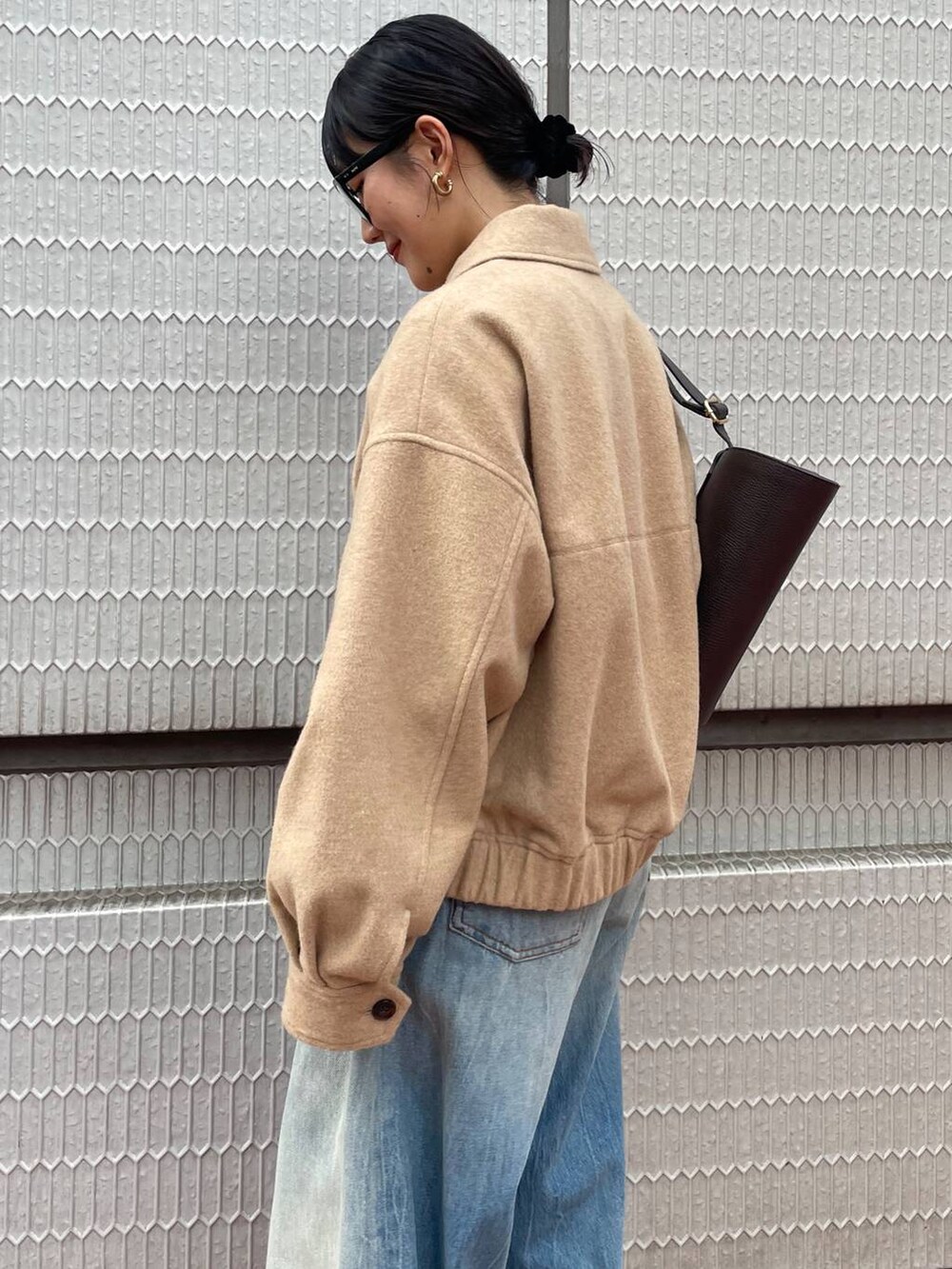 ブラウン系のショルダーバッグ、ブルー系のデニムパンツ、ベージュ系のブルゾンを着用したレディースの冬コーディネートの4枚目の写真