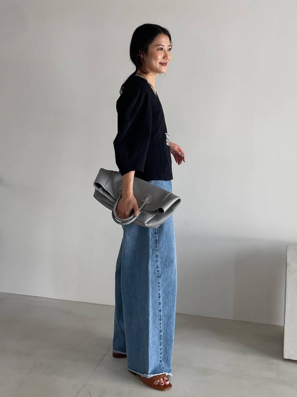 ブルー系のデニムパンツ、ブラック系のTシャツ/カットソー、グレー系のショルダーバッグを着用したレディースの春コーディネートの3枚目の写真