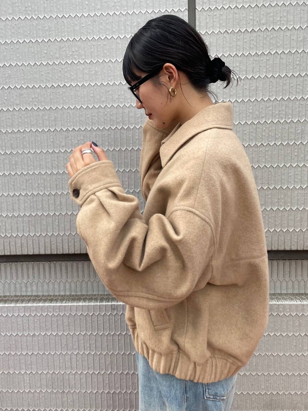 ブラウン系のショルダーバッグ、ブルー系のデニムパンツ、ベージュ系のブルゾンを着用したレディースの冬コーディネートの3枚目の写真