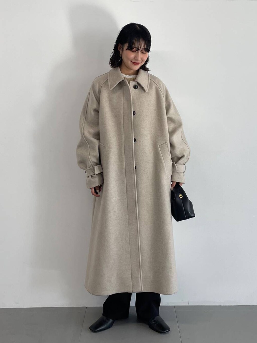 ブラック系のその他パンツ、ベージュ系のステンカラーコート、ベージュ系のニット/セーターを着用したレディースの冬コーディネートの2枚目の写真