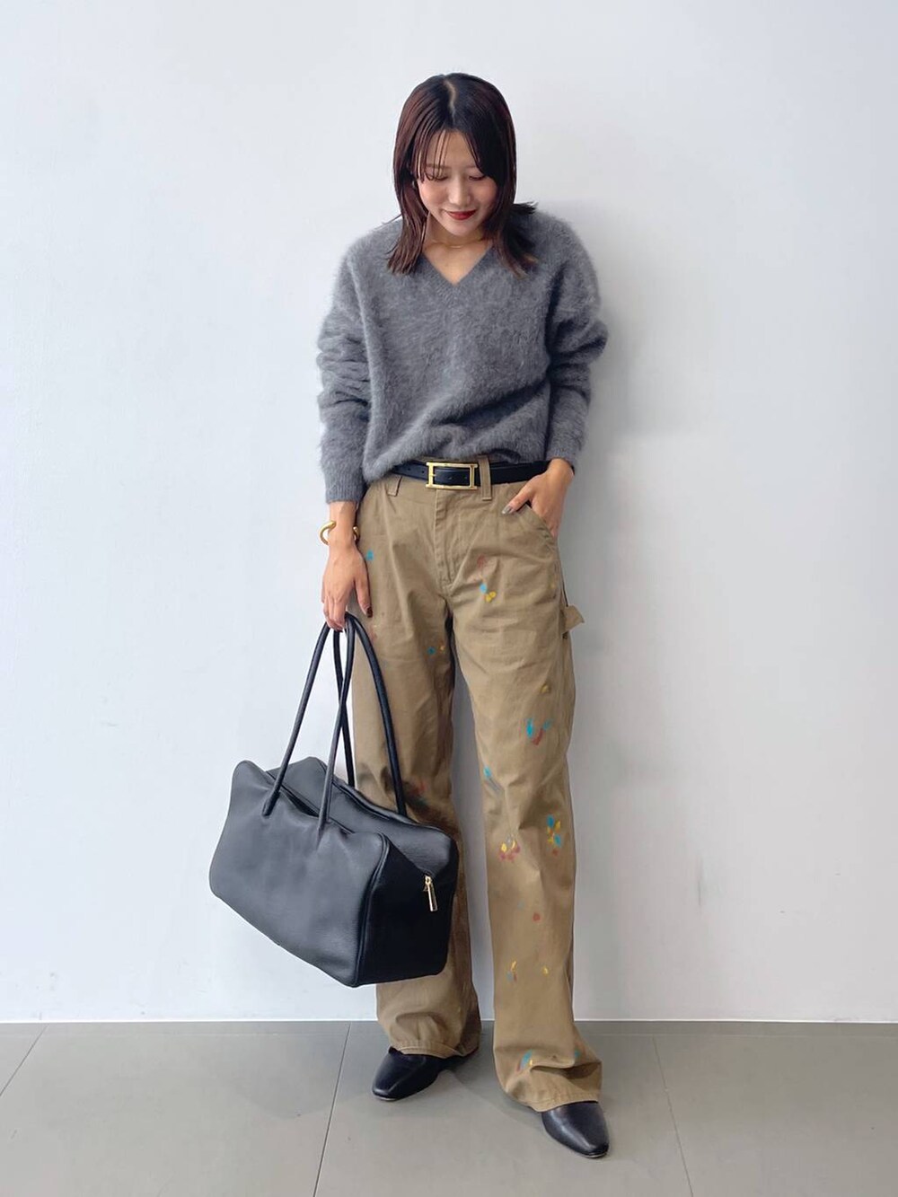 グレー系のニット/セーター、ブラック系のボストンバッグ、ブラック系のブーツを着用したレディースの秋コーディネートの2枚目の写真