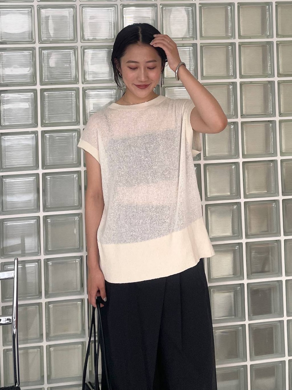 ブラック系のハンドバッグ、ブラック系のその他パンツ、ホワイト系のニット/セーターを着用したレディースの夏コーディネートの5枚目の写真