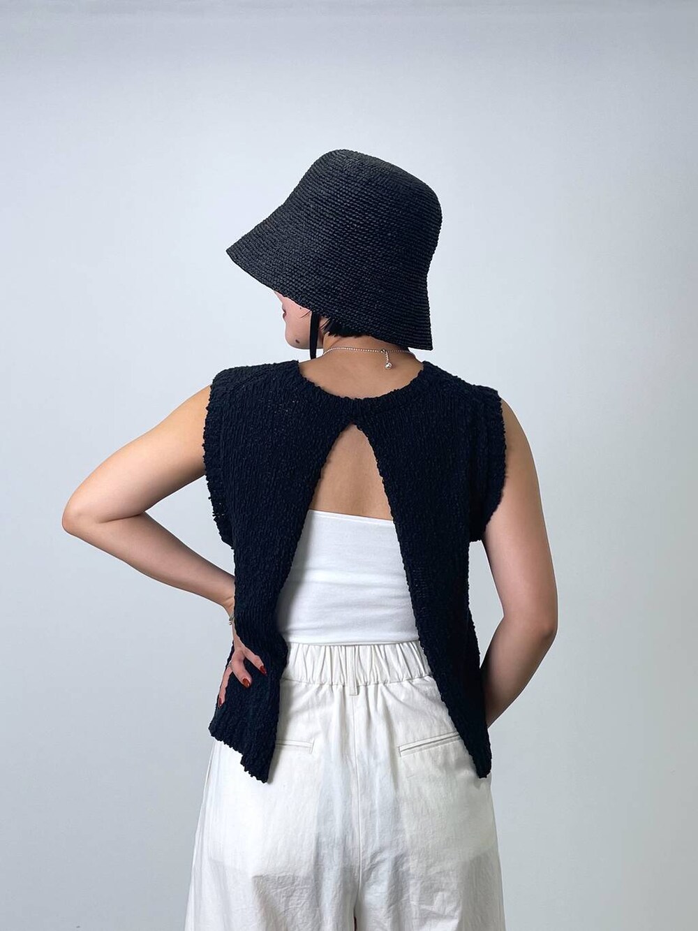 ブラック系のニット/セーター、ホワイト系のその他パンツ、ブラック系のハットを着用したレディースの春コーディネートの4枚目の写真