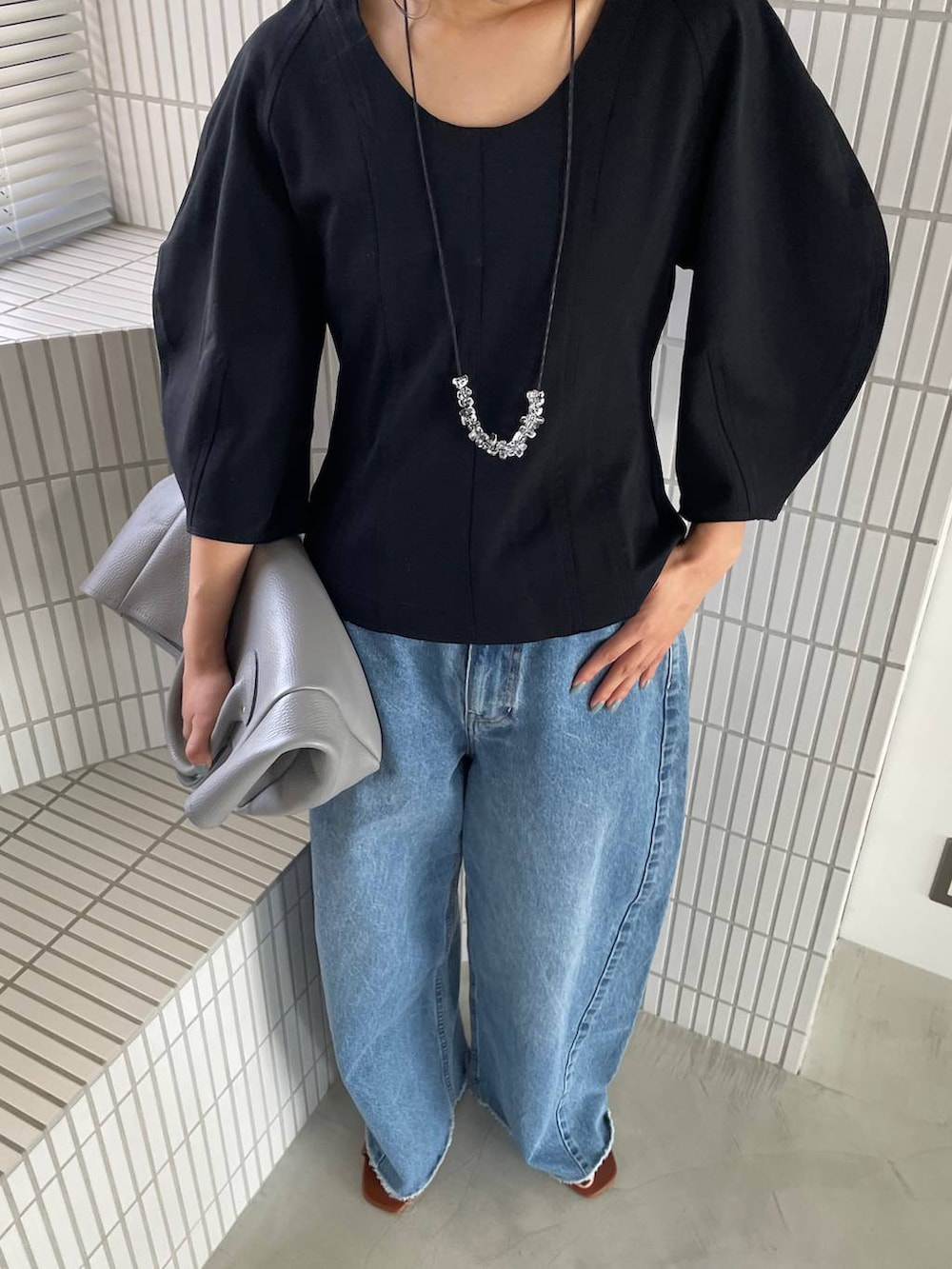 ブルー系のデニムパンツ、ブラック系のTシャツ/カットソー、グレー系のショルダーバッグを着用したレディースの春コーディネートの6枚目の写真