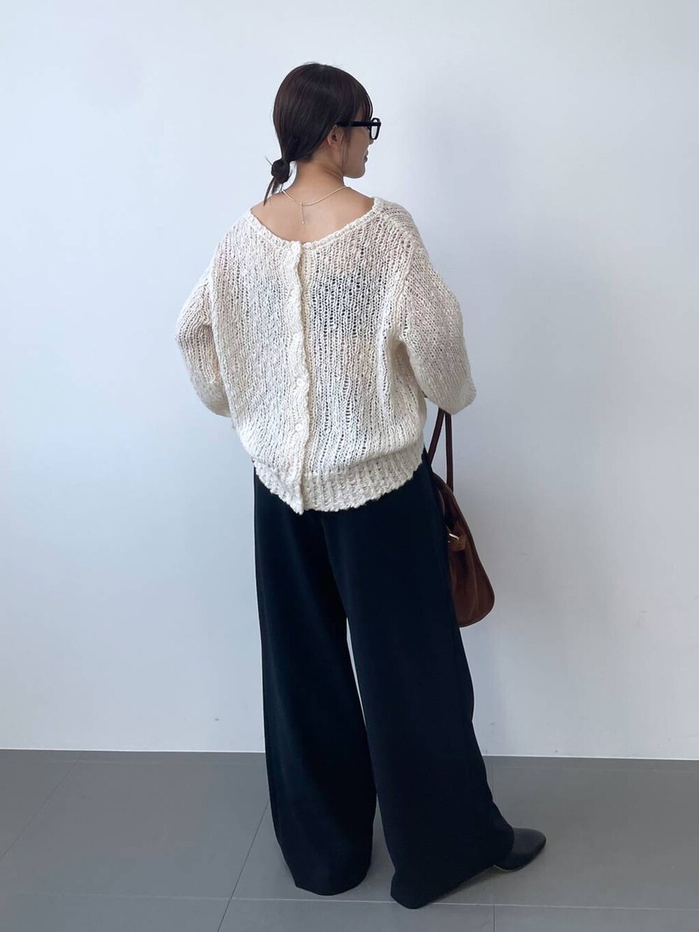 ホワイト系のニット/セーター、ブラック系のその他パンツ、ブラウン系のボストンバッグを着用したレディースの夏コーディネートの3枚目の写真