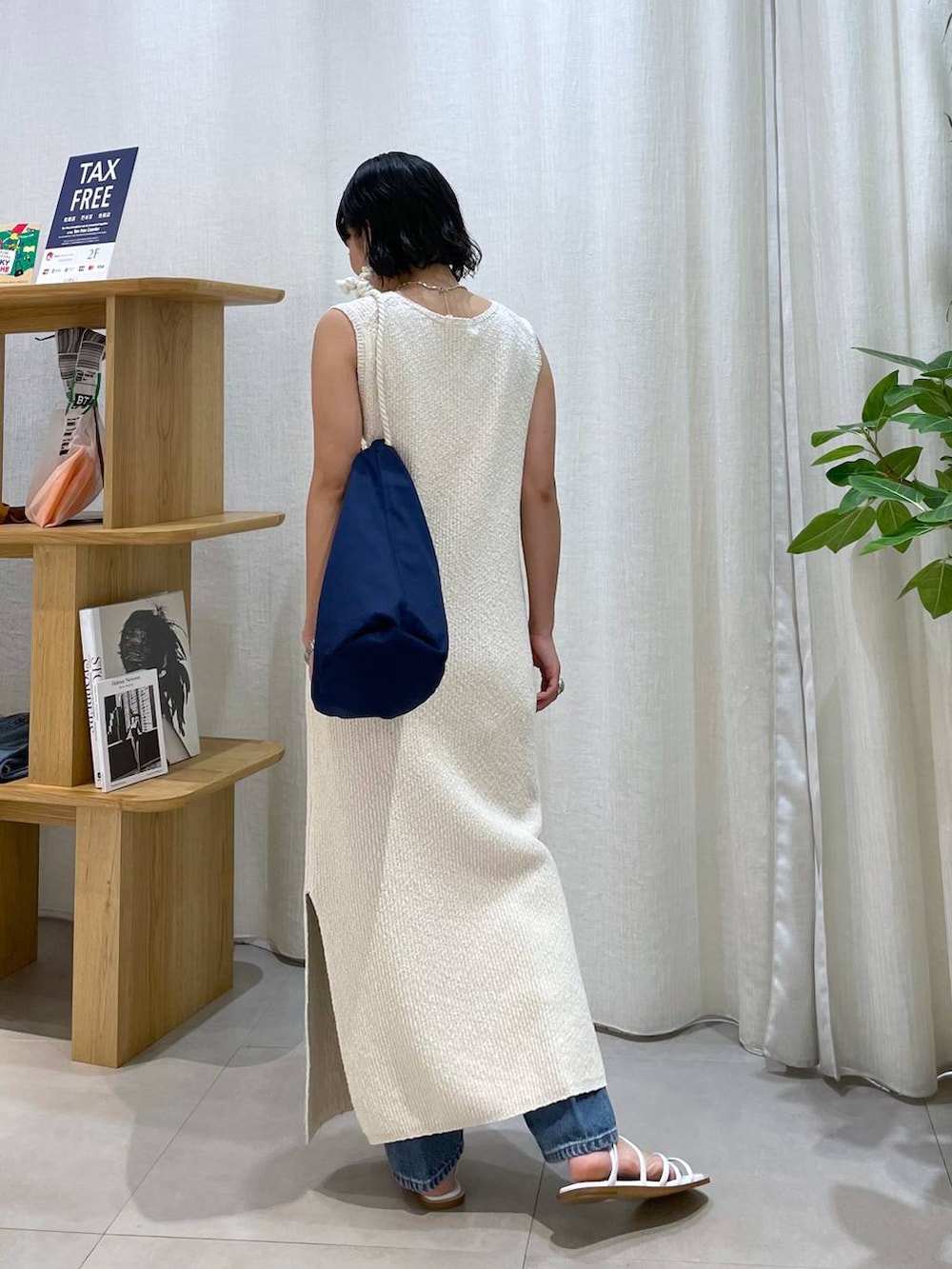 ブルー系のハンドバッグ、ホワイト系のサンダル、ブルー系のデニムパンツを着用したレディースの夏コーディネートの4枚目の写真