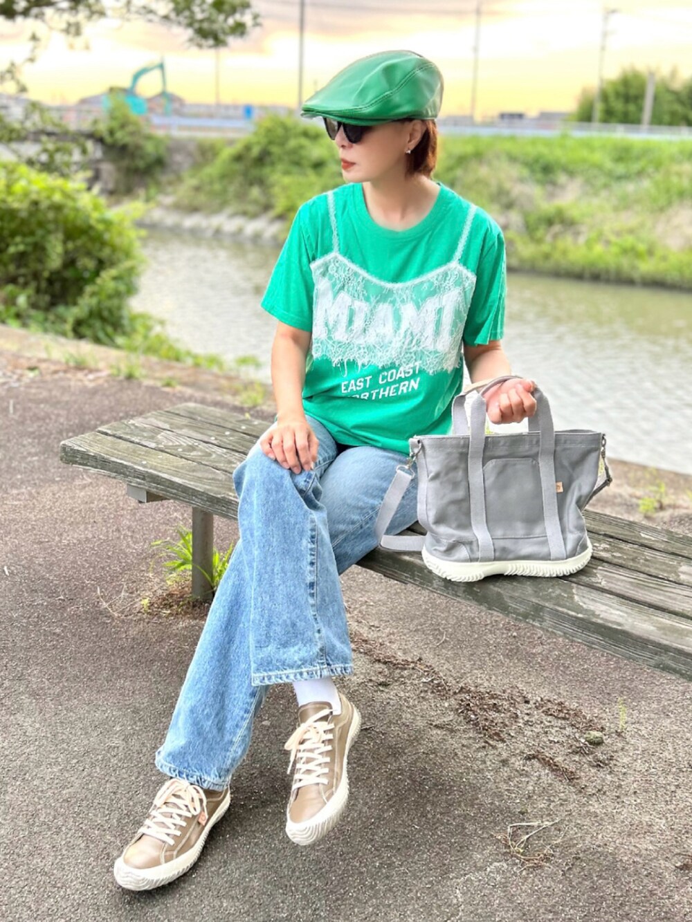 グレー系のトートバッグ、グリーン系のTシャツ/カットソー、ブルー系のデニムパンツを着用したレディースの春コーディネートの4枚目の写真