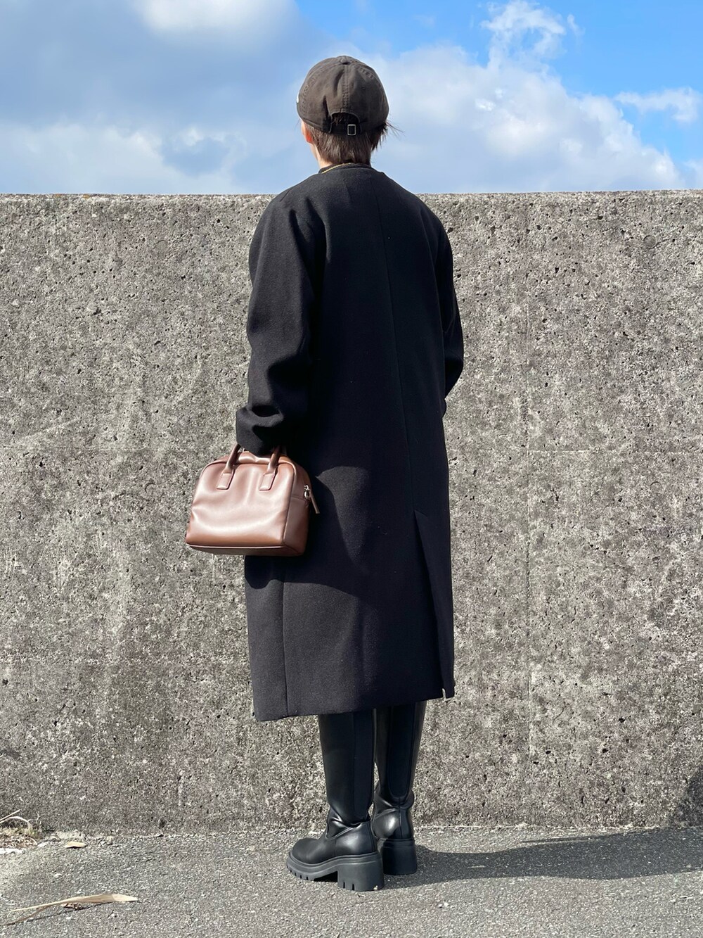 ブラック系のノーカラーコート、ブラック系のニット/セーター、ブラック系のその他パンツを着用したレディースの冬コーディネートの4枚目の写真