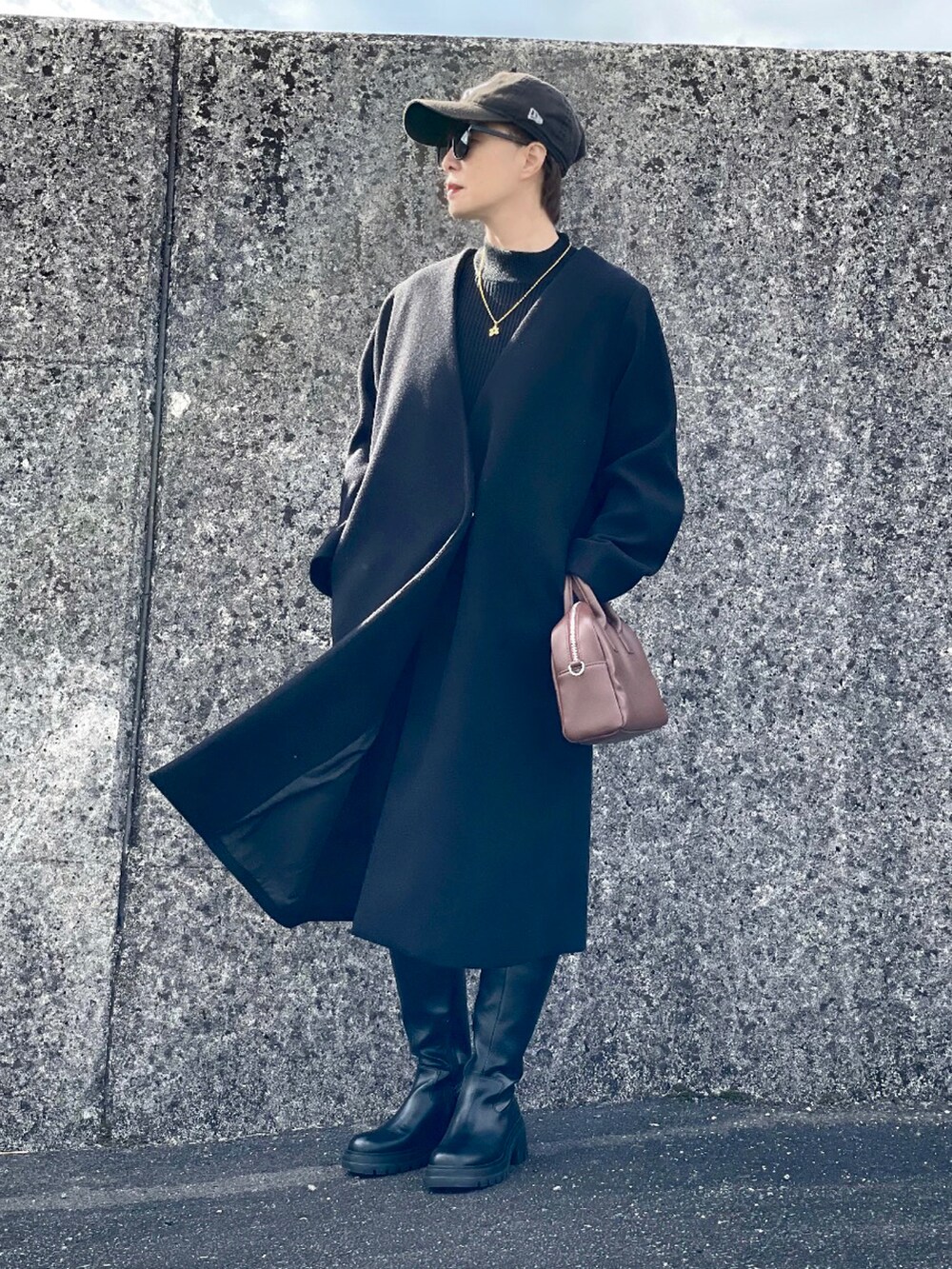 ブラック系のノーカラーコート、ブラック系のニット/セーター、ブラック系のその他パンツを着用したレディースの冬コーディネートの3枚目の写真