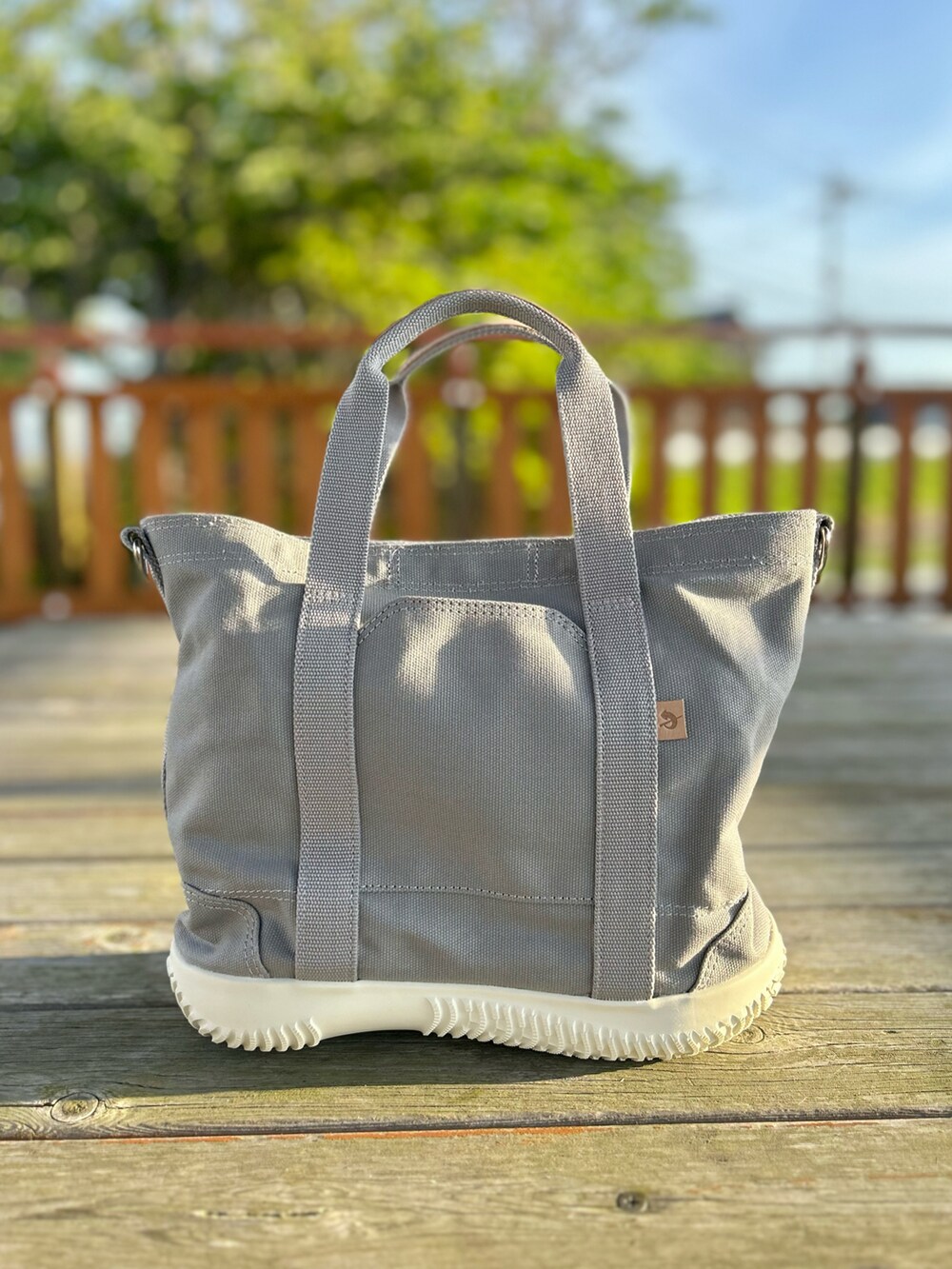 グレー系のトートバッグ、グリーン系のTシャツ/カットソー、ブルー系のデニムパンツを着用したレディースの春コーディネートの3枚目の写真