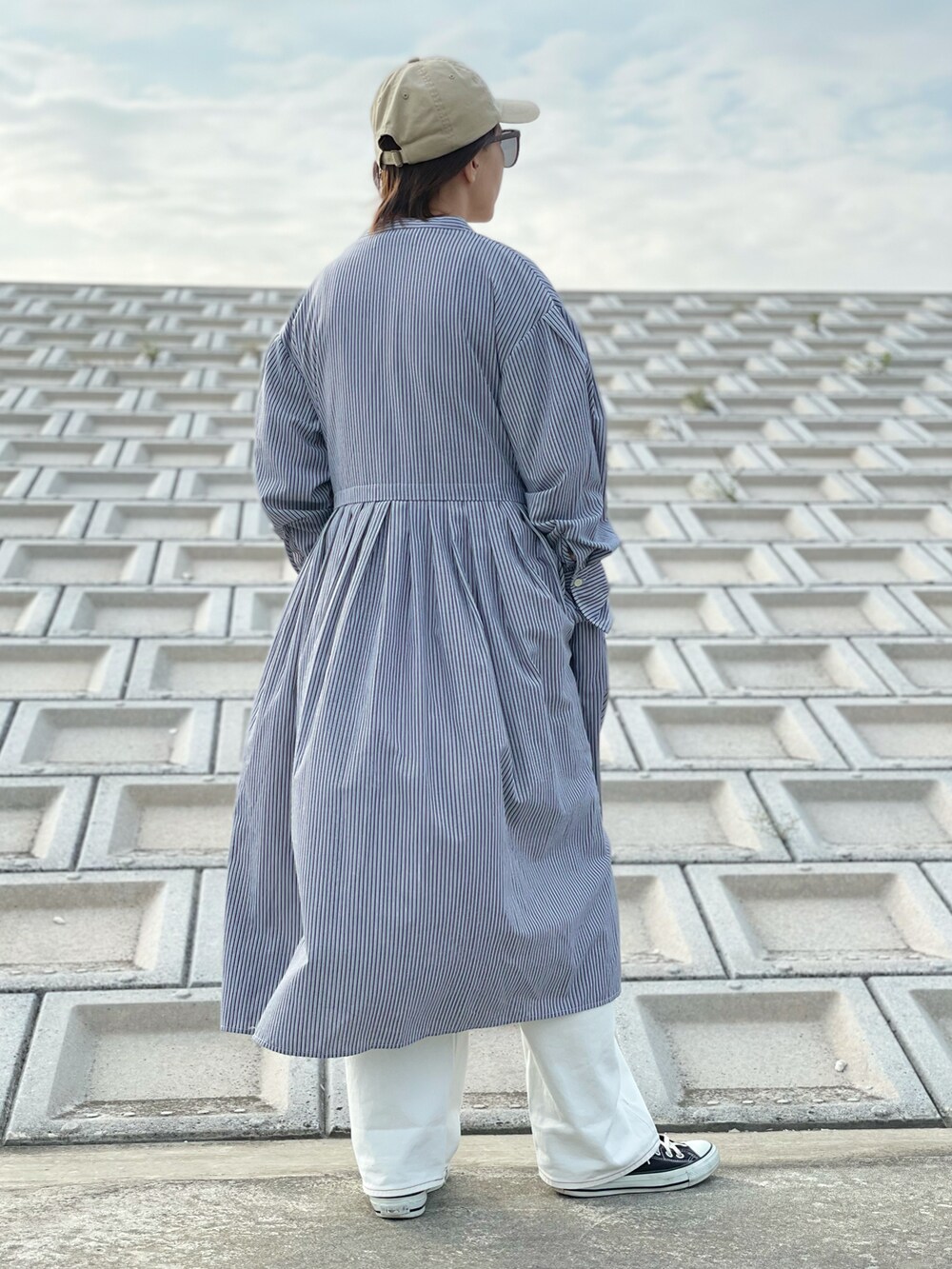 ホワイト系のデニムパンツ、ブラック系のスニーカー、ベージュ系のTシャツ/カットソーを着用したレディースの春コーディネートの2枚目の写真