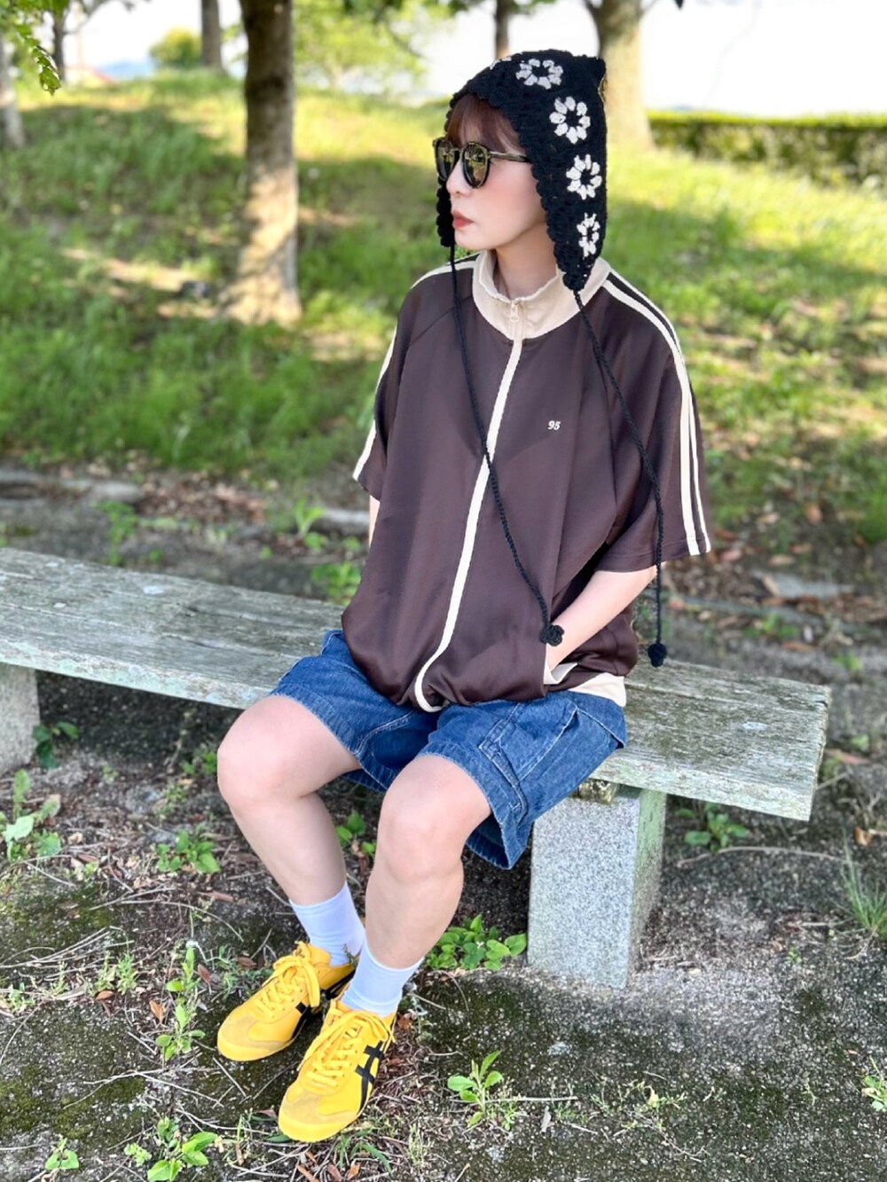 ブラウン系のジャージ、ブルー系のパンツ、イエロー系のスニーカーを着用したレディースの夏コーディネートの2枚目の写真