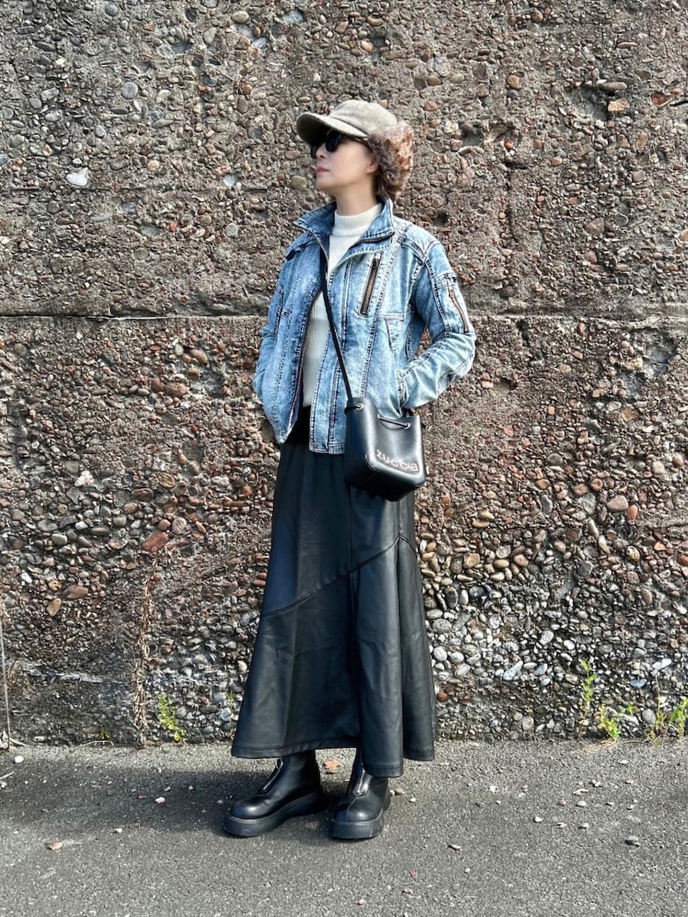ブルー系のデニムジャケット、ブラック系のスカート、ブラック系のブーツを着用したレディースの秋コーディネートの4枚目の写真