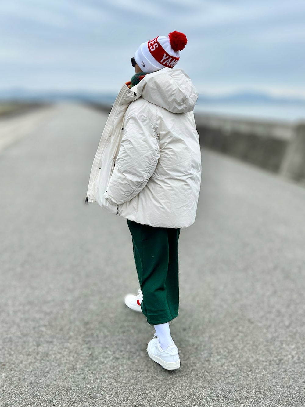 ホワイト系のダウンジャケット/コート、ホワイト系のスニーカー、グリーン系のワンピースを着用したレディースの冬コーディネートの4枚目の写真