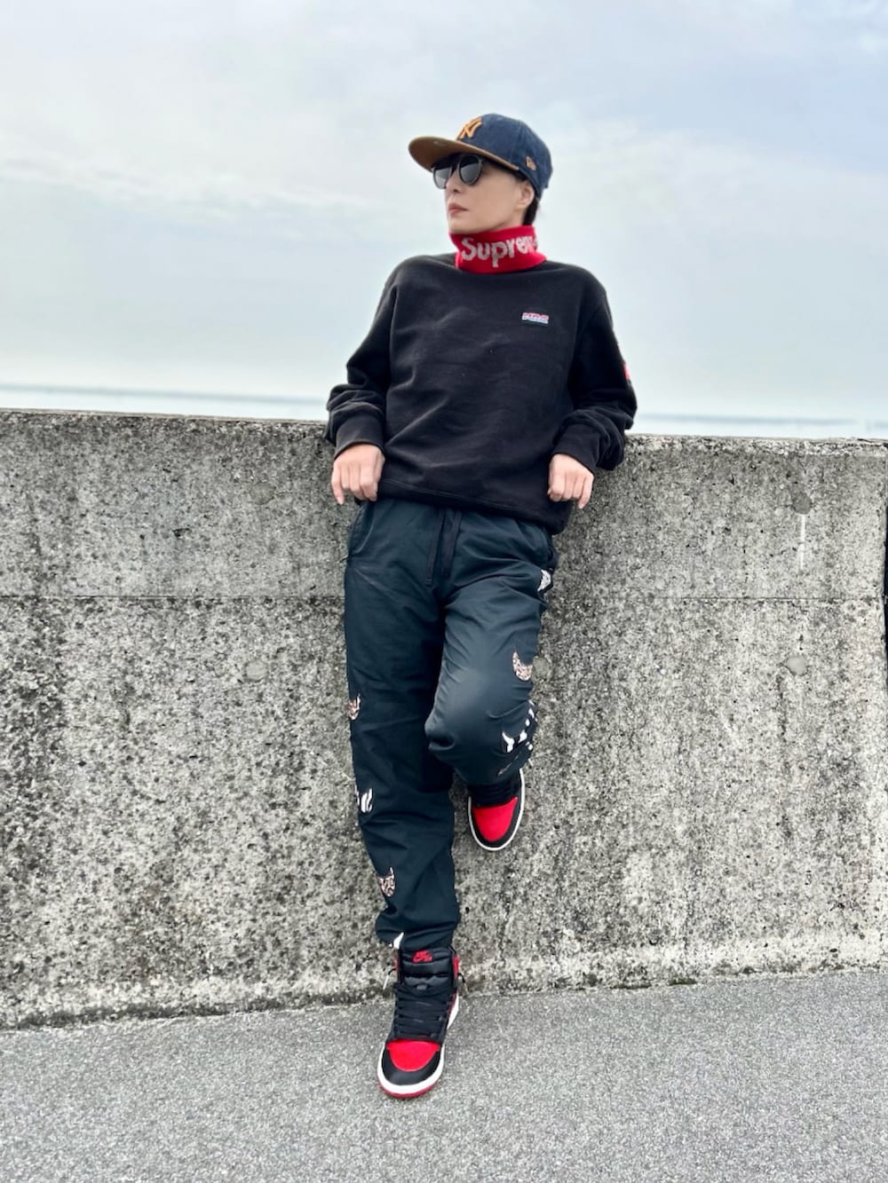 ブラック系のスウェット、ブラック系のパンツ、レッド系のスニーカーを着用したレディースの冬コーディネートの3枚目の写真