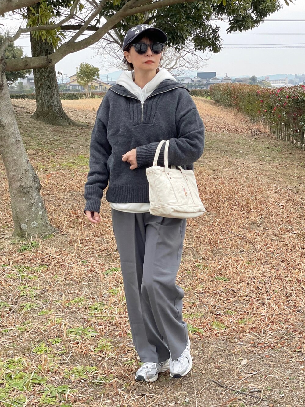 ホワイト系のトートバッグ、グレー系のニット/セーター、ホワイト系のパーカーを着用したレディースの冬コーディネートの2枚目の写真