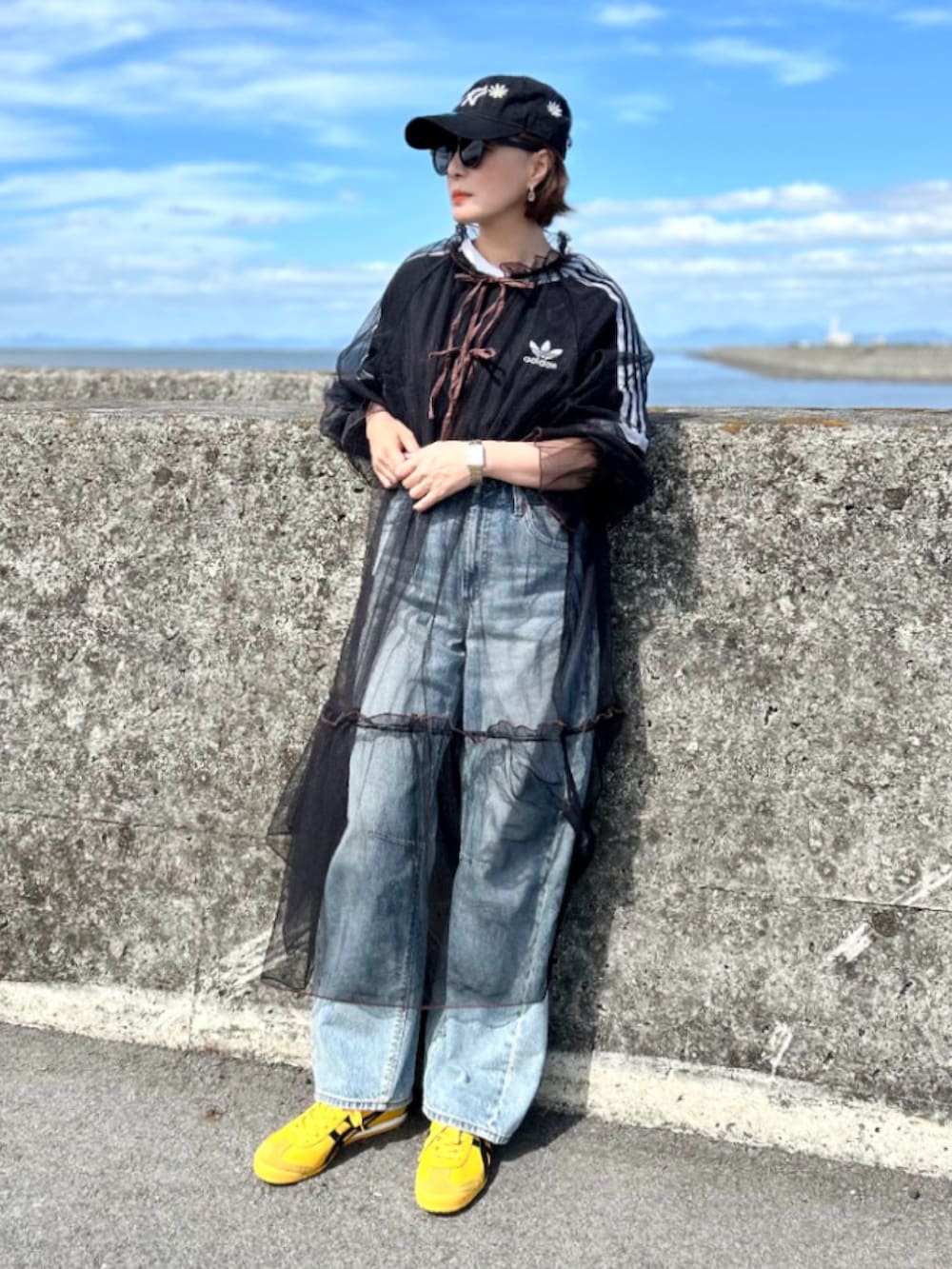 ブラック系のTシャツ/カットソー、ブラック系のワンピース、ブルー系のデニムパンツを着用したレディースの秋コーディネートの4枚目の写真