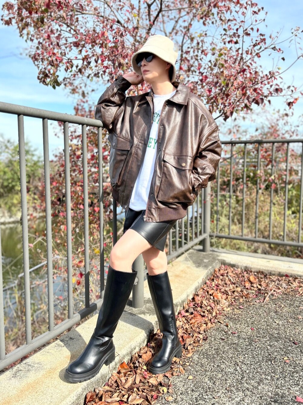 ブラウン系のブルゾン、ホワイト系のスウェット、ブラック系のパンツを着用したレディースの秋コーディネートの2枚目の写真