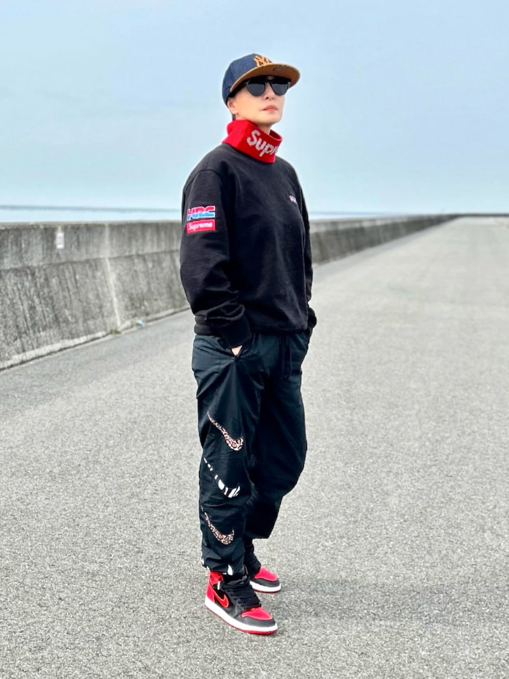 ブラック系のスウェット、ブラック系のパンツ、レッド系のスニーカーを着用したレディースの冬コーディネートの2枚目の写真