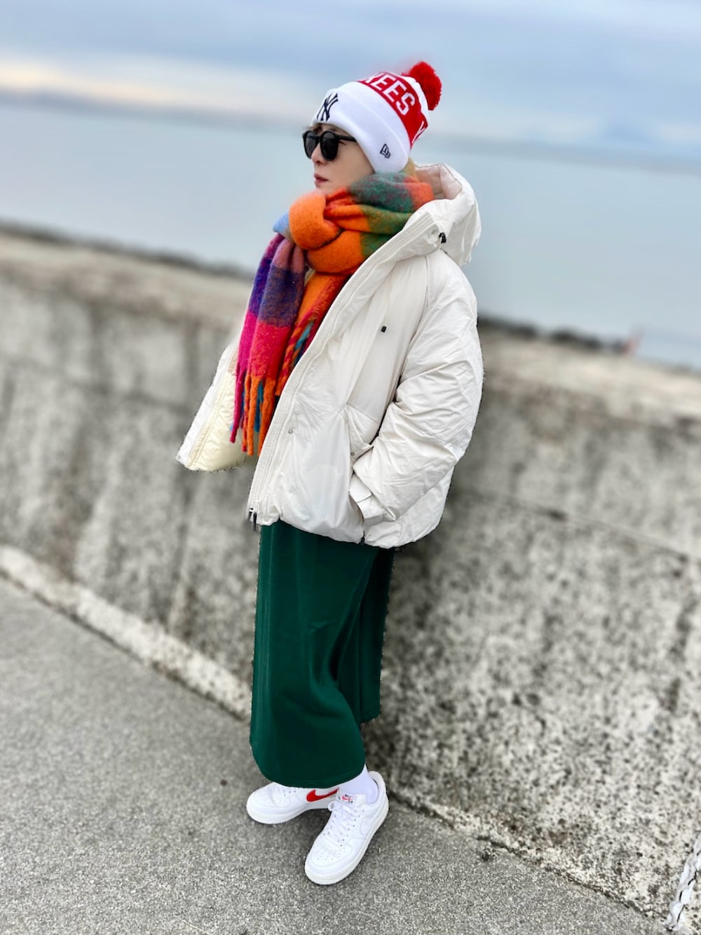 ホワイト系のダウンジャケット/コート、ホワイト系のスニーカー、グリーン系のワンピースを着用したレディースの冬コーディネートの2枚目の写真