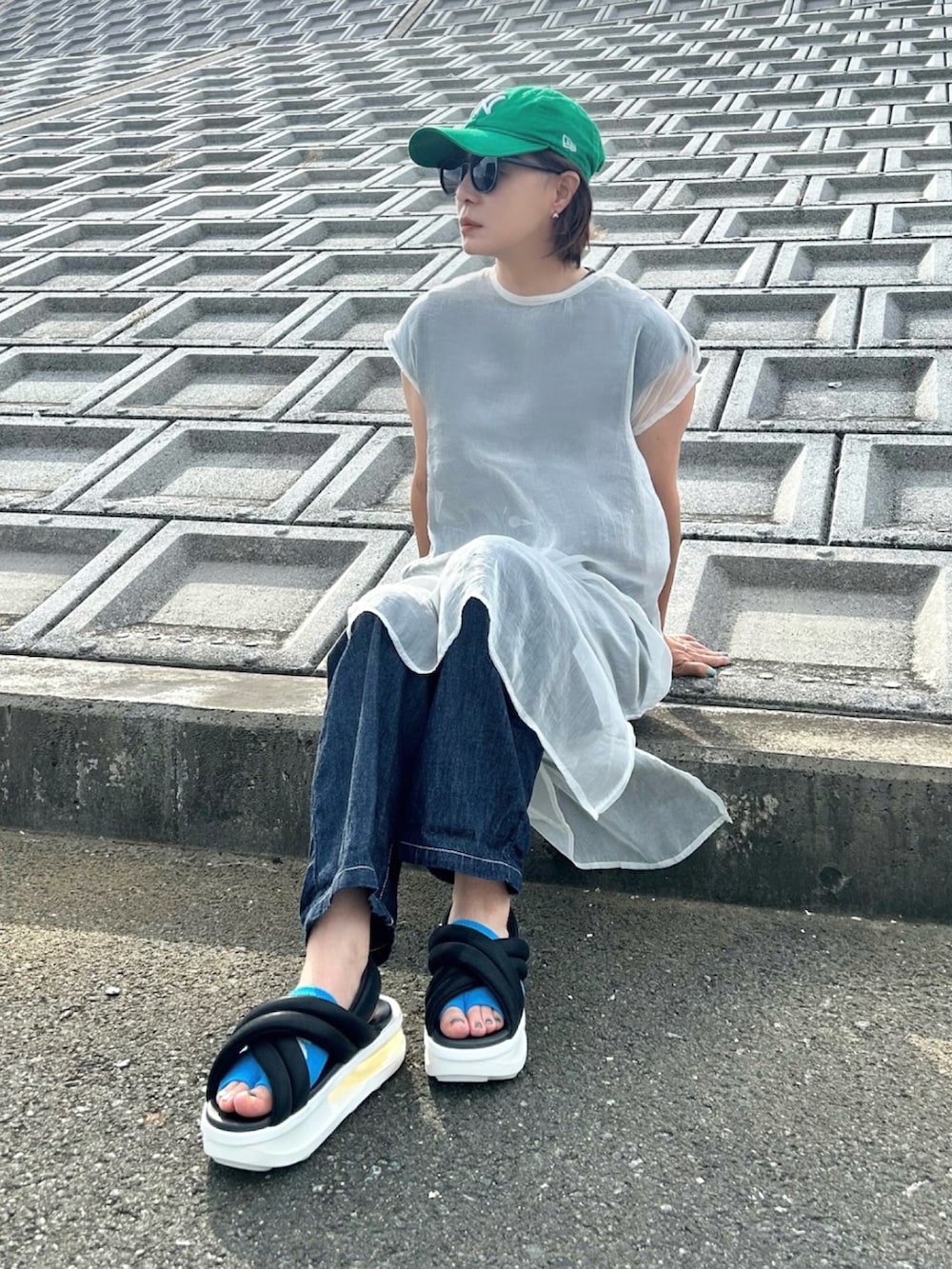 ブラック系のサンダル、ブルー系のサロペット/オーバーオール、ホワイト系のワンピースを着用したレディースの夏コーディネートの3枚目の写真