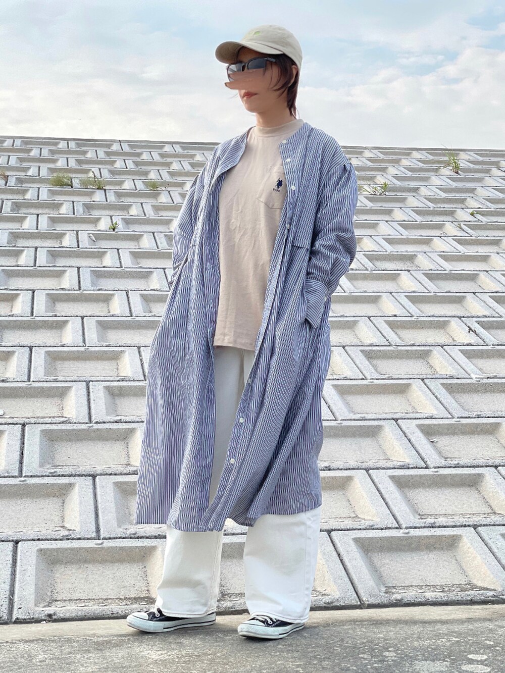 ホワイト系のデニムパンツ、ブラック系のスニーカー、ベージュ系のTシャツ/カットソーを着用したレディースの春コーディネートの3枚目の写真