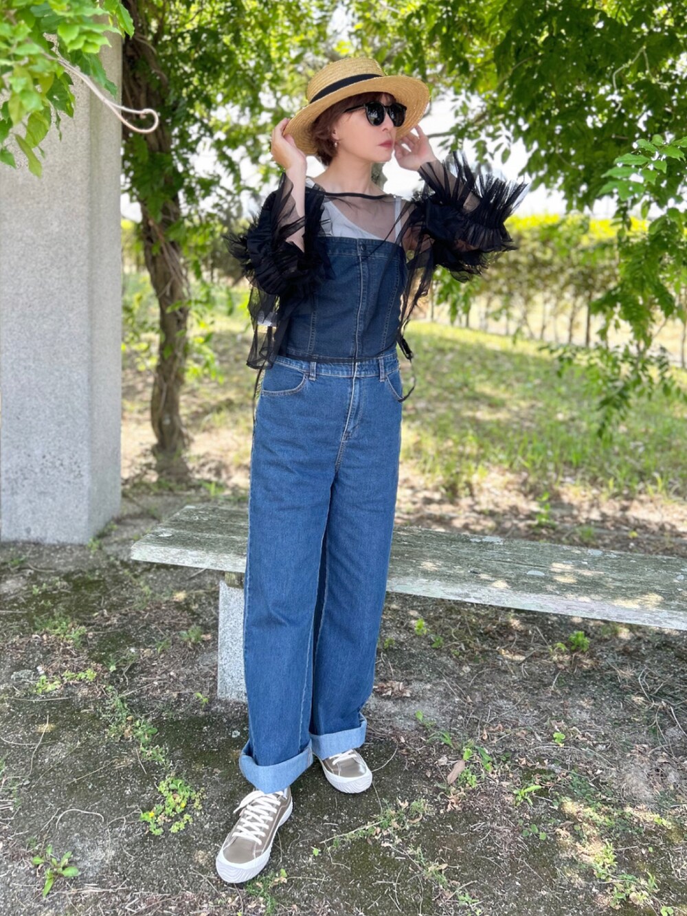 グレー系のスニーカー、ブラック系のシャツ/ブラウス、ブルー系のサロペット/オーバーオールを着用したレディースの春コーディネートの2枚目の写真